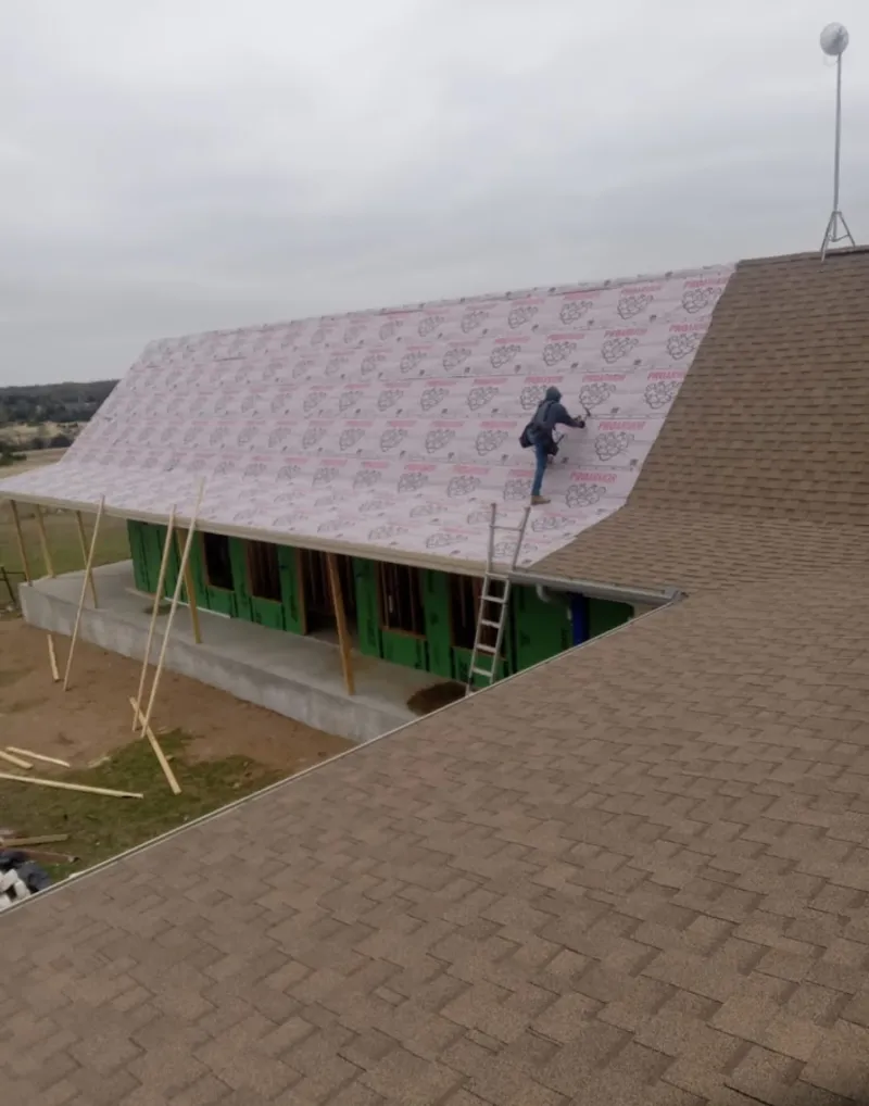 Worker preparing underlayment for a metal roof installation in Mooresville